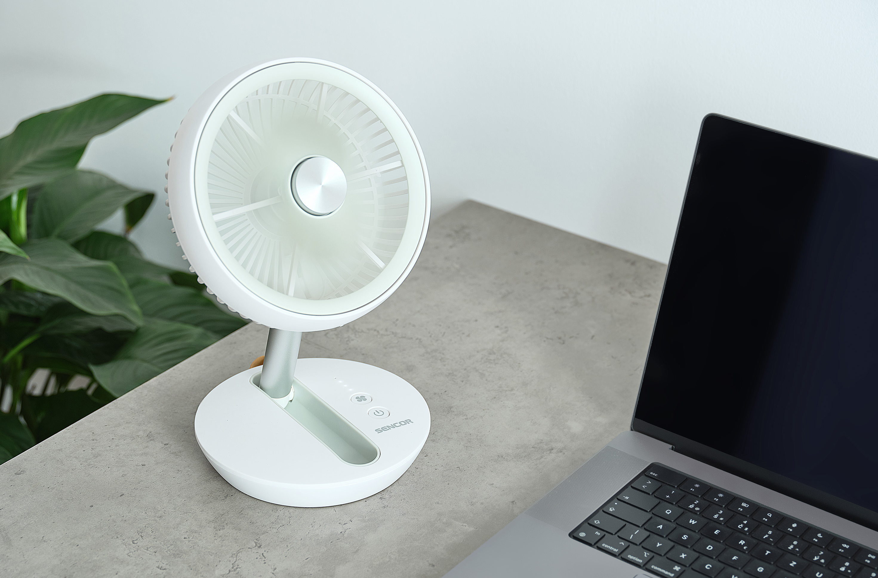 Fehér asztali ventilátor, laptop a szürke asztalon, növény.