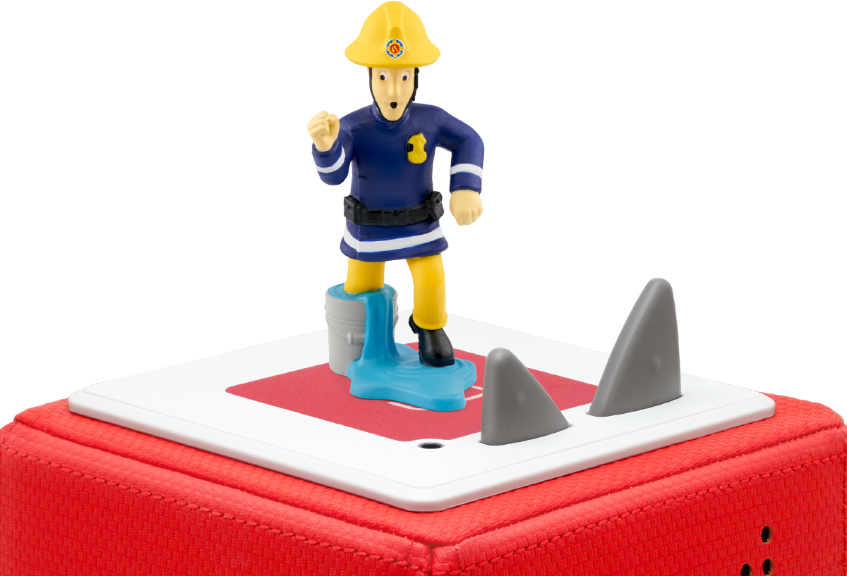 Eine Spielzeug-Feuerwehrmannfigur auf einer roten Box mit Haifischflossen. Schwarzer Hintergrund.