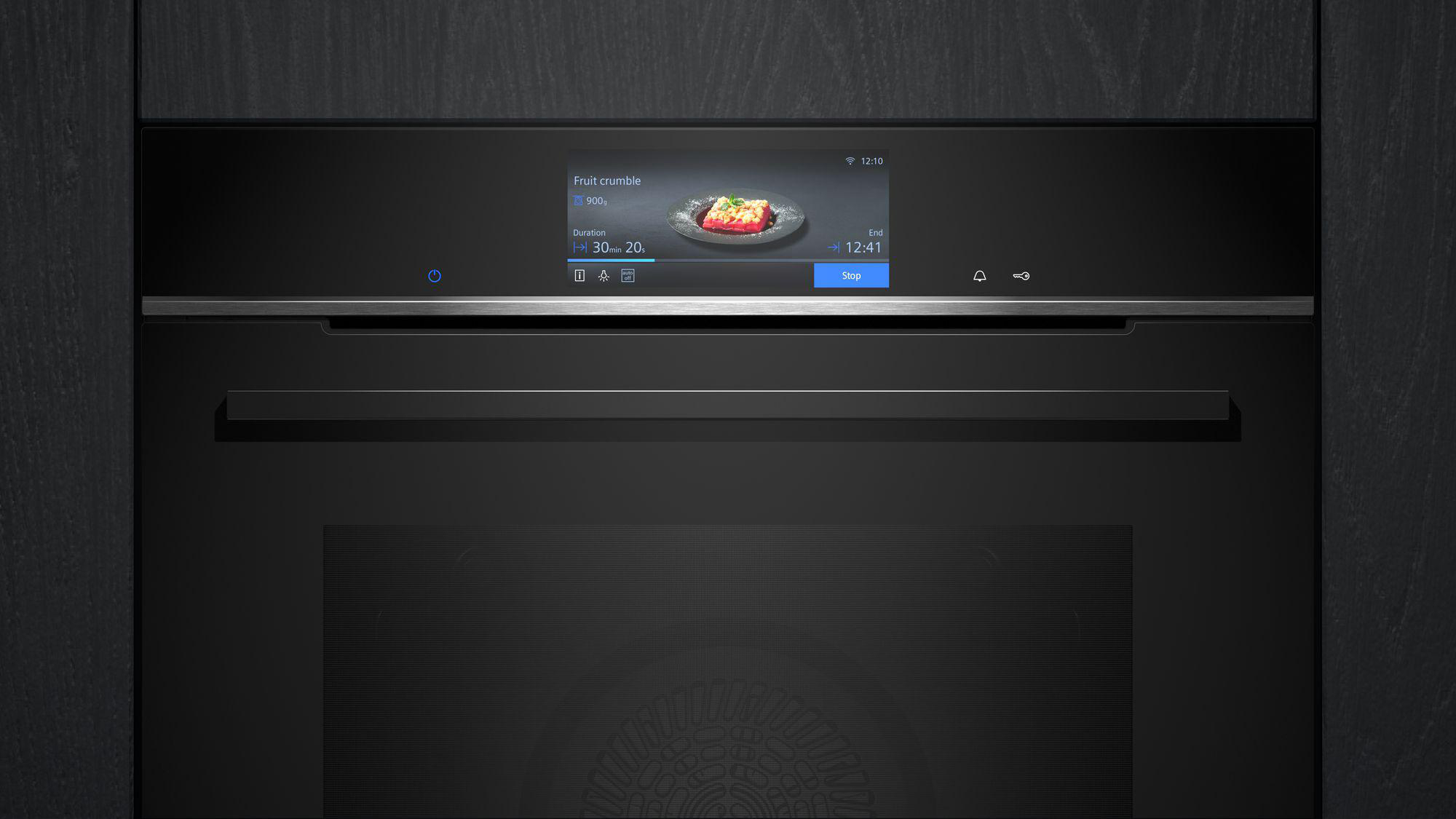 Schwarzer Backofen mit Digitalanzeige, die ein Rezept für Obststreusel anzeigt. Schwarzer Hintergrund.
