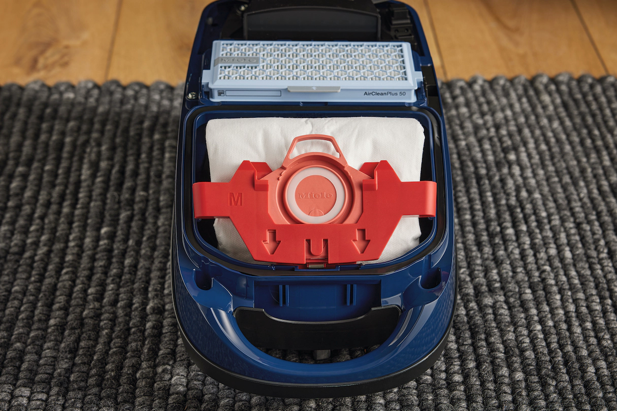 Offener Miele-Staubsauger. Innen: Staubbeutel, roter Halter und Luftfilter.