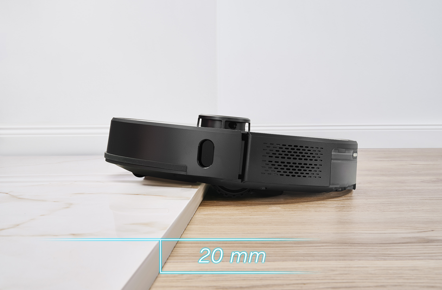 Fekete robotporszívó a padlón. A szöveg 20 mm-es magasságot jelez.
