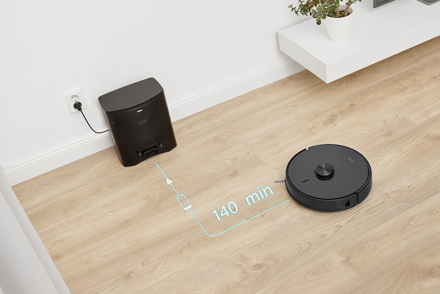 Egy fekete robotporszívó fapadlón, fekete töltőállomással és töltőkábellel.