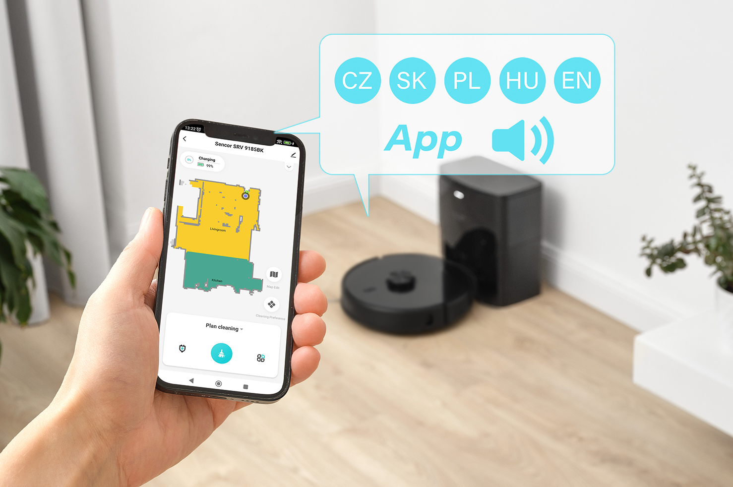 Egy személy egy okostelefont tart, amely egy szoba takarítási térképét mutatja. A háttérben egy robotporszívó.