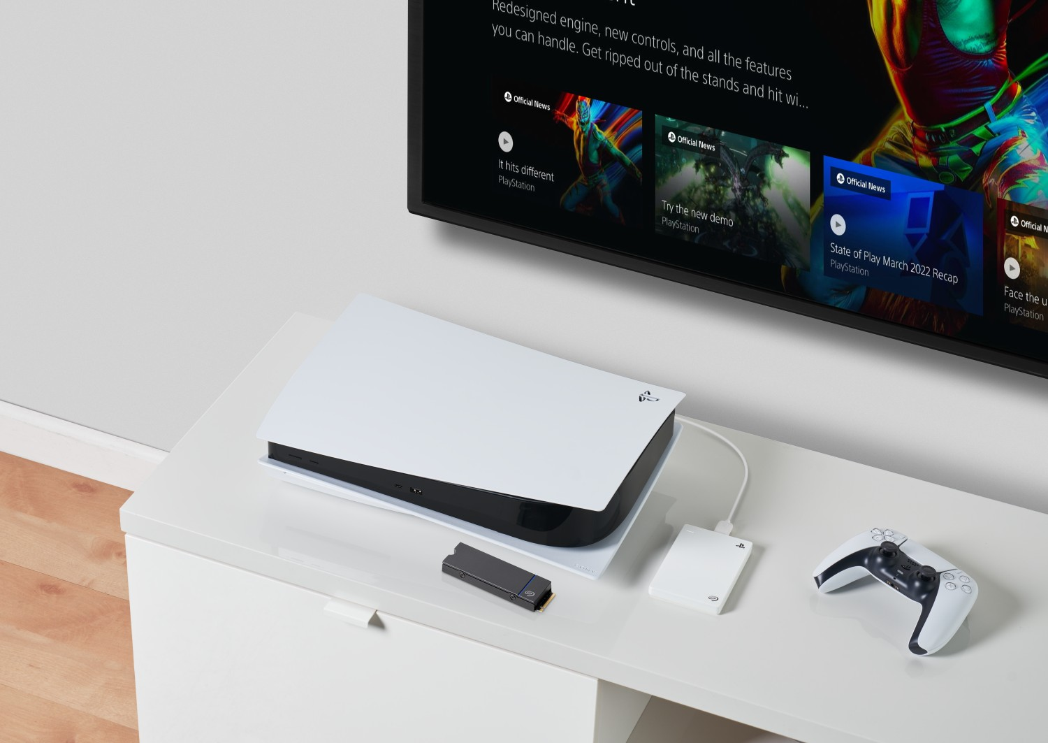 Playstation 5 Konsole, Controller und externe Festplatte auf einem weißen Tisch. TV im Hintergrund.