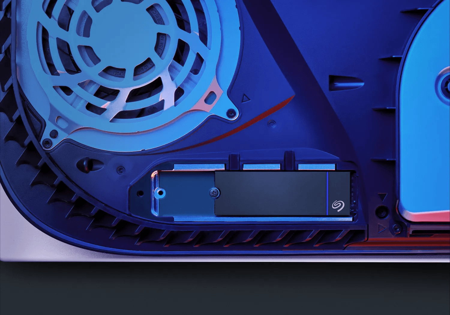 Vista interna di una PlayStation 5, che mostra la ventola, un pannello blu e un SSD nero.