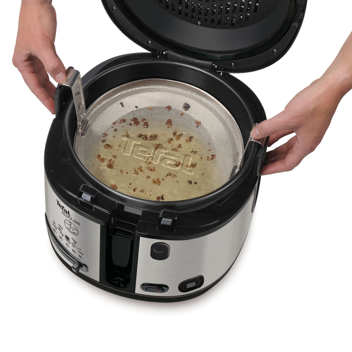 Dłonie wyjmujące metalowe sitko z frytownicy.
