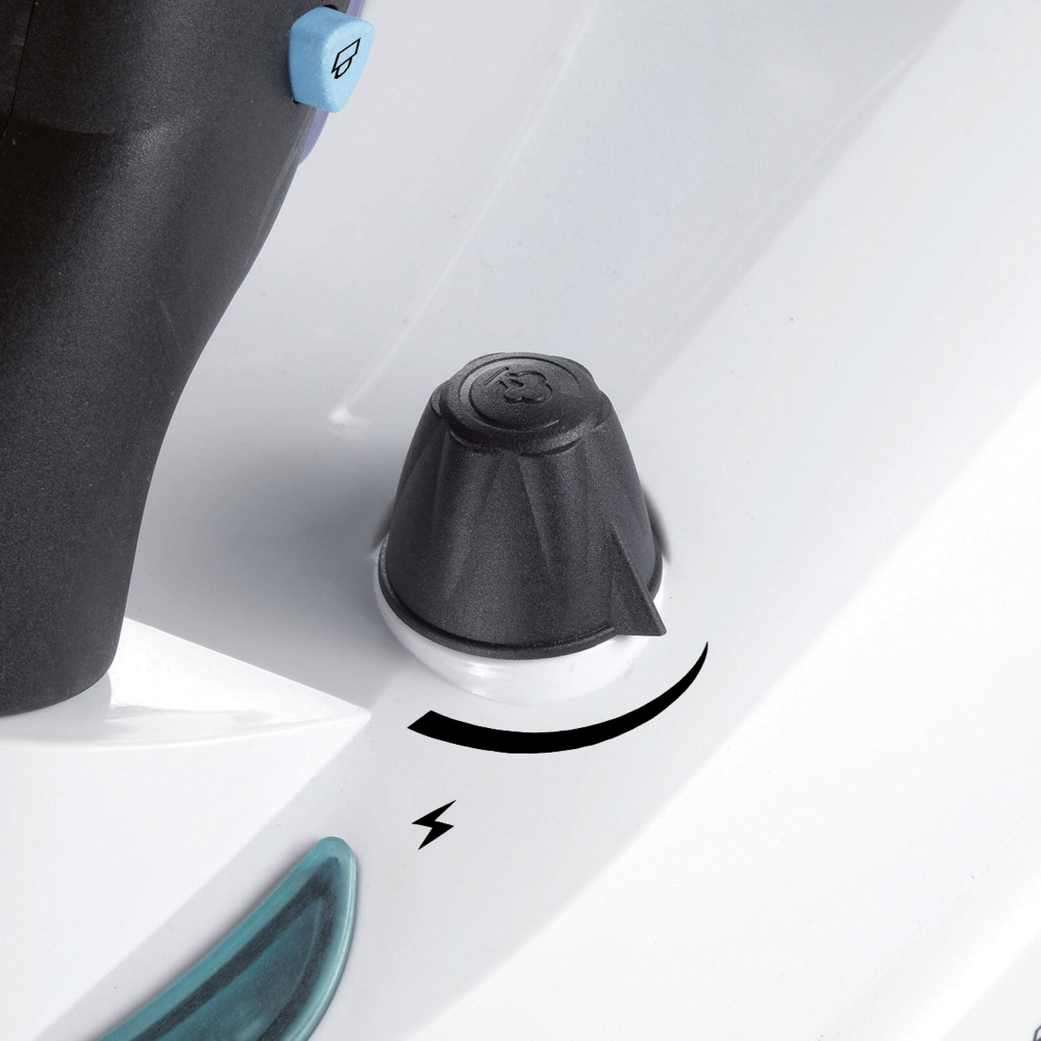 Biała powierzchnia z czarnym pokrętłem i niebieskim przyciskiem, ze strzałką wskazującą kierunek.