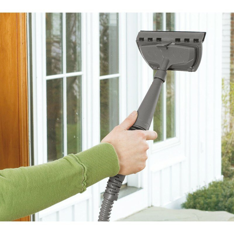 Osoba czyszcząca okno urządzeniem do czyszczenia szyb. W tle biały dom.