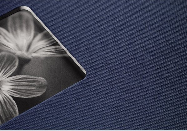 Zbliżenie granatowej tkaniny ze zdjęciem w wycięciu. Na zdjęciu są kwiaty.