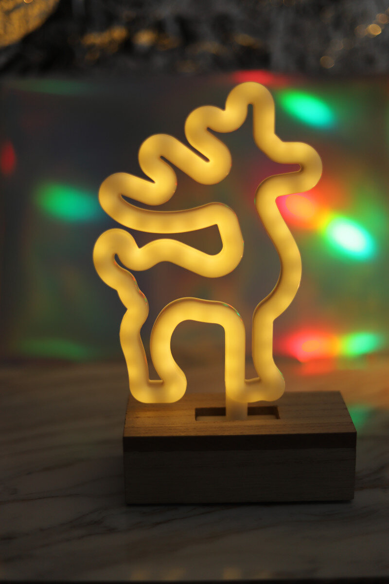 Neonowe światło renifera na drewnianej podstawie, oświetlające kolorowe tło.