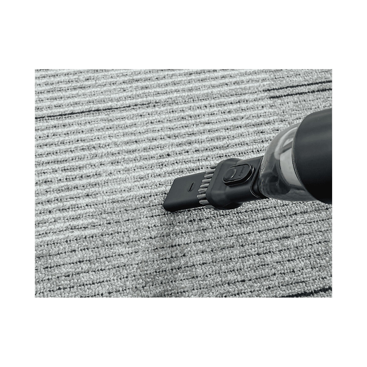 Głowica odkurzacza czyszcząca szary dywan. Zbliżenie na szczotkę.