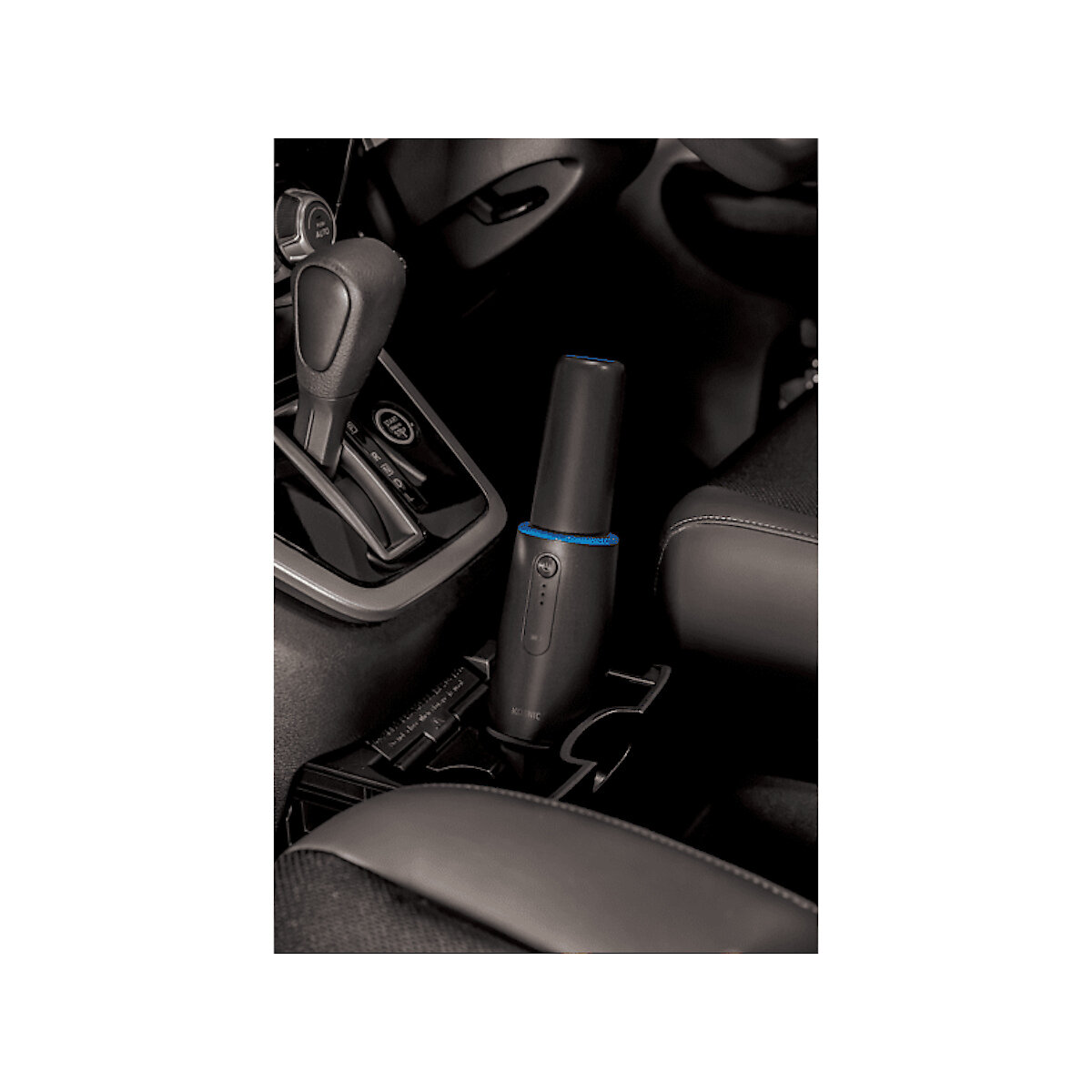 Czarny odkurzacz w konsoli środkowej samochodu. Widoczne czarne wnętrze samochodu.