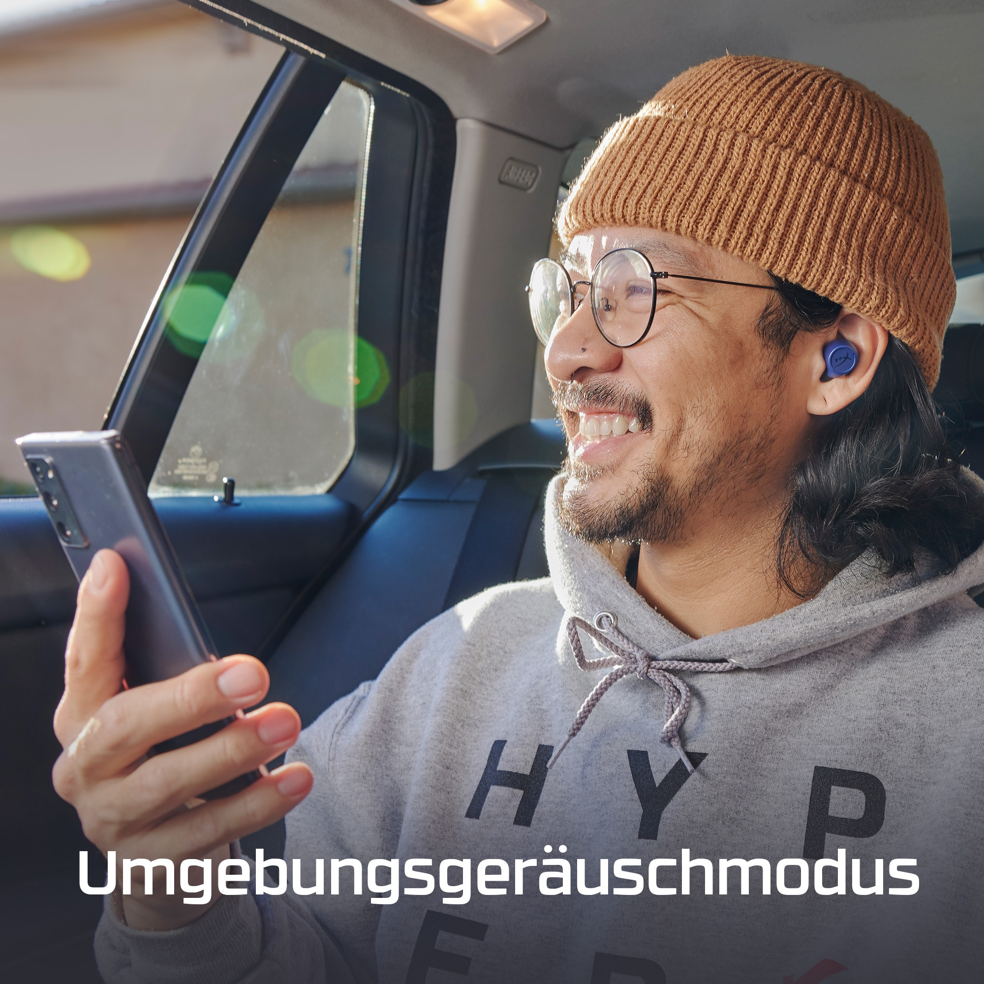 Mann im Auto, Brille und Mütze, benutzt das Telefon.