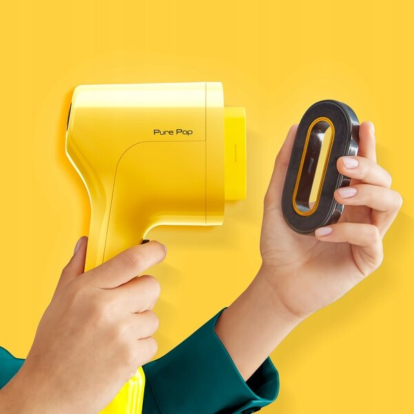 Żółta suszarka do włosów Pure Pop i czarny dodatek. Ręka trzyma suszarkę i dodatek.