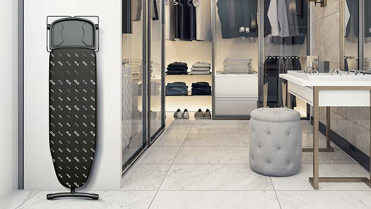 Deska do prasowania, otwarta, w pokoju. Szafa i okno w tle.