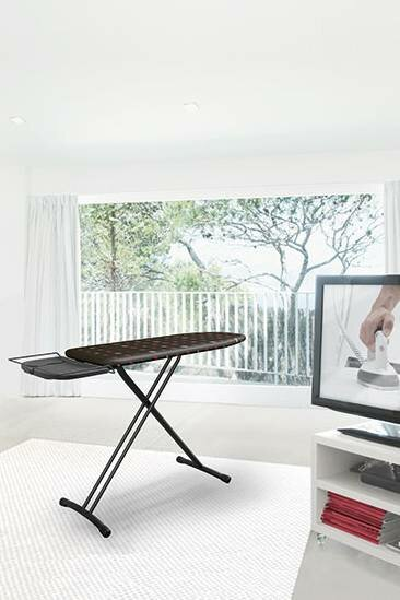 Deska do prasowania w jasnym pokoju, telewizor w tle.