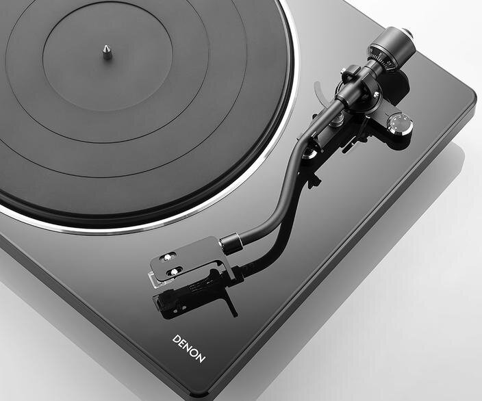 Czarny gramofon z czarną płytą. Ma ramię i czarną podstawę z logo DENON.