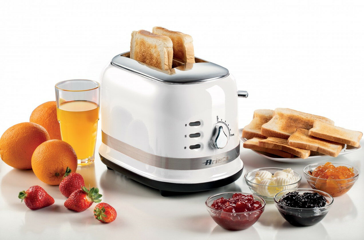 Biały toster z dwoma tostami, pomarańczami, sokiem, truskawkami, dżemem.
