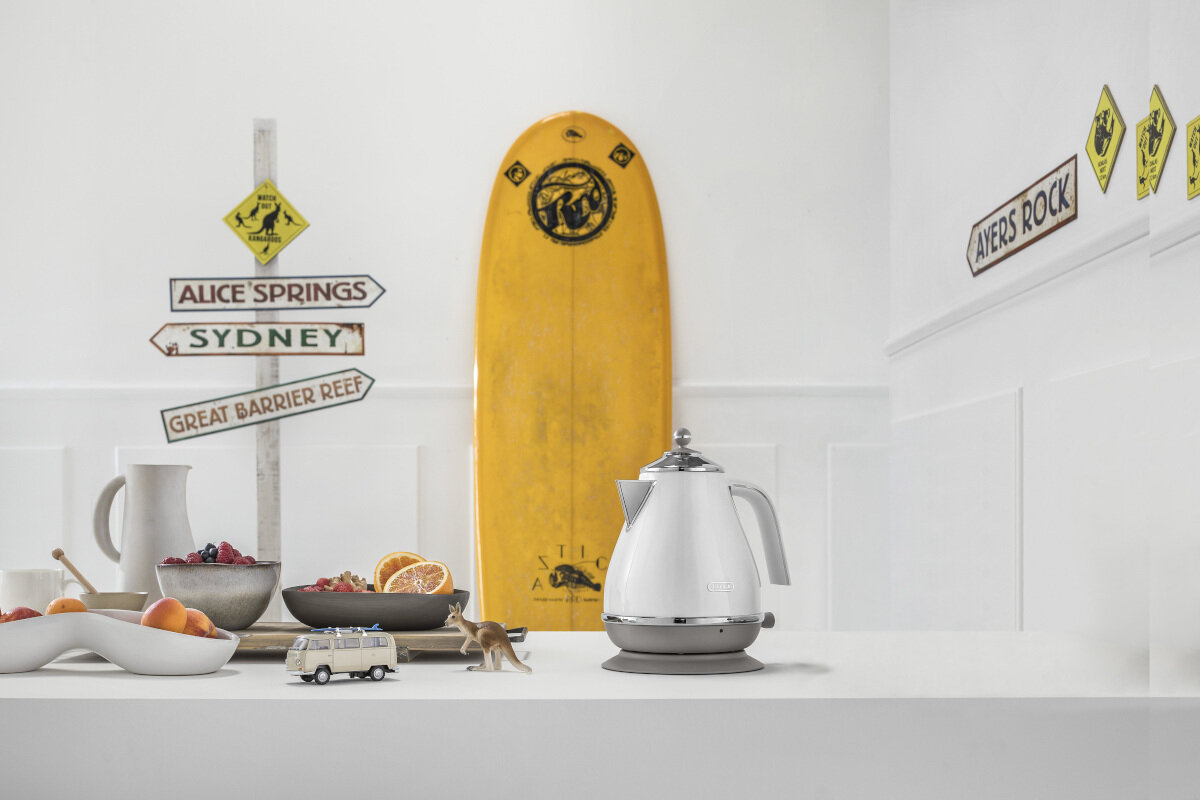 Scena kuchenna: Biały czajnik, deska surfingowa, znaki dla Alice Springs i Ayers Rock.
