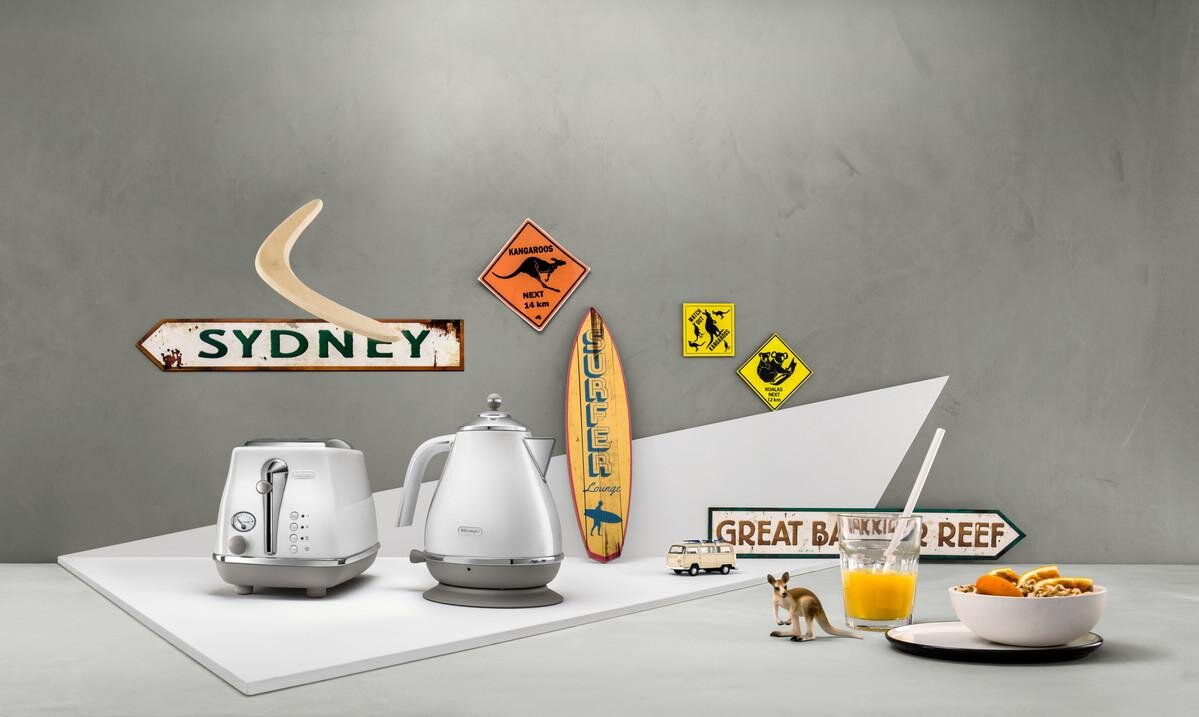 Scena śniadaniowa z tosterem, czajnikiem, znakiem deski surfingowej i figurką kangura.