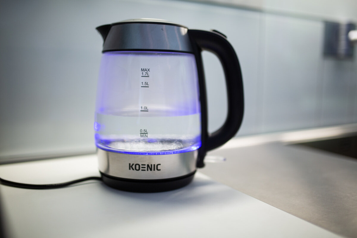 Szklany czajnik elektryczny z wodą w środku i niebieskimi światłami.