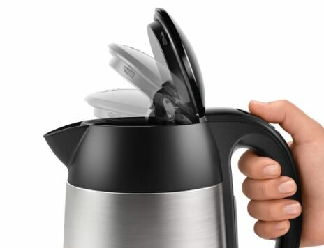 Zbliżenie czarnego i srebrnego czajnika elektrycznego z pokrywką otwieraną przez rękę osoby.