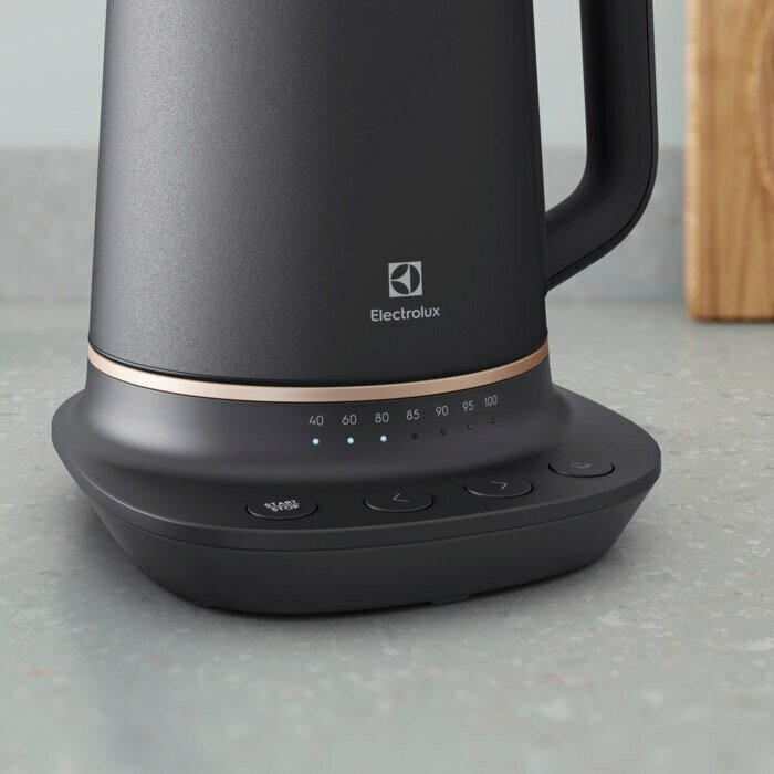 Czarny czajnik elektryczny z podstawą i przyciskami sterowania. Szary blat, z logo Electrolux.