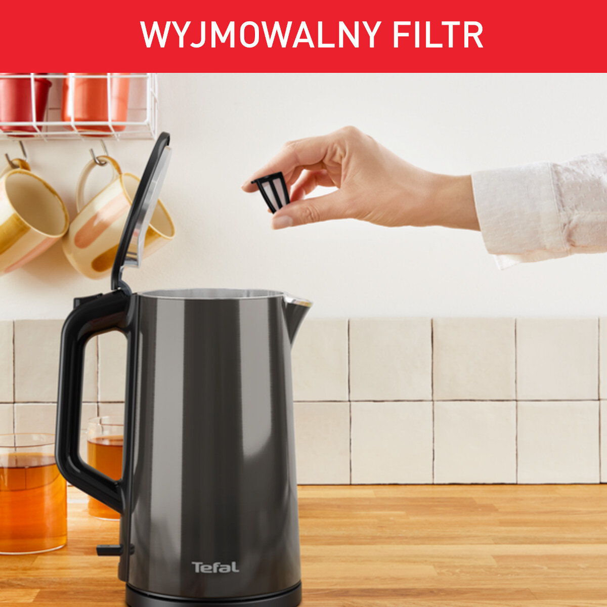 Czarny i szary czajnik z wyjmowanym filtrem. Ręka wyjmuje filtr.