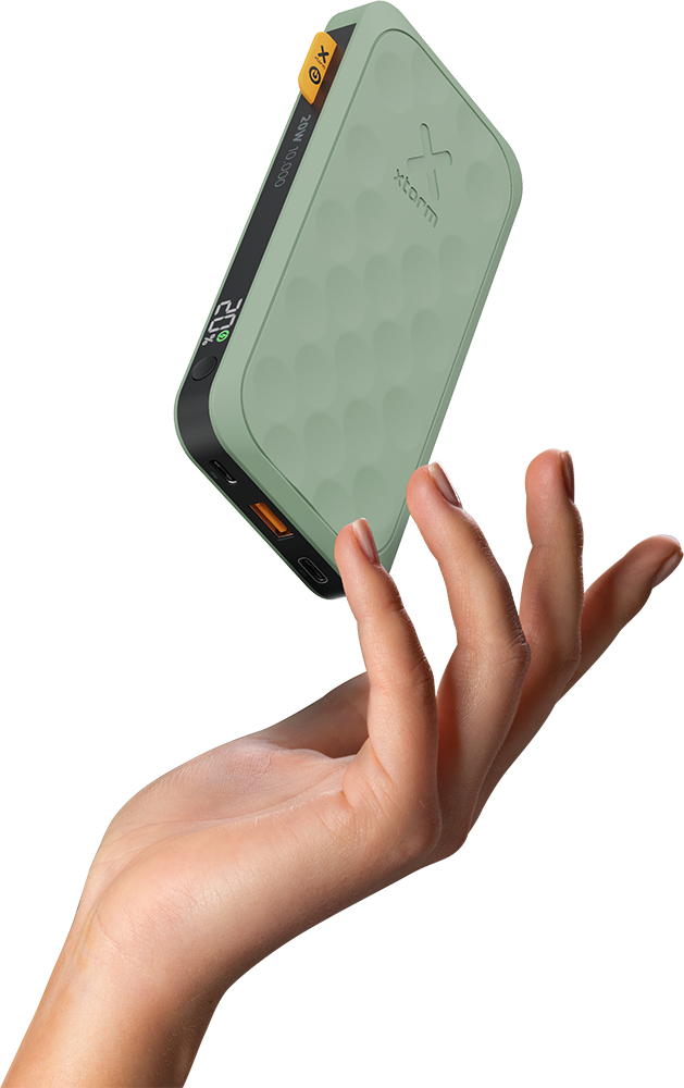 A hand holding a green and black power bank. The power bank is in the air.