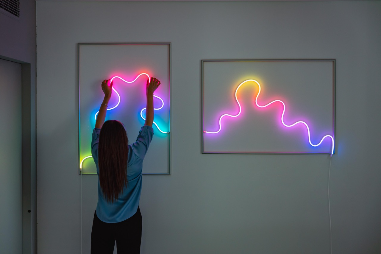 Donna che regola luci al neon colorate su un muro.