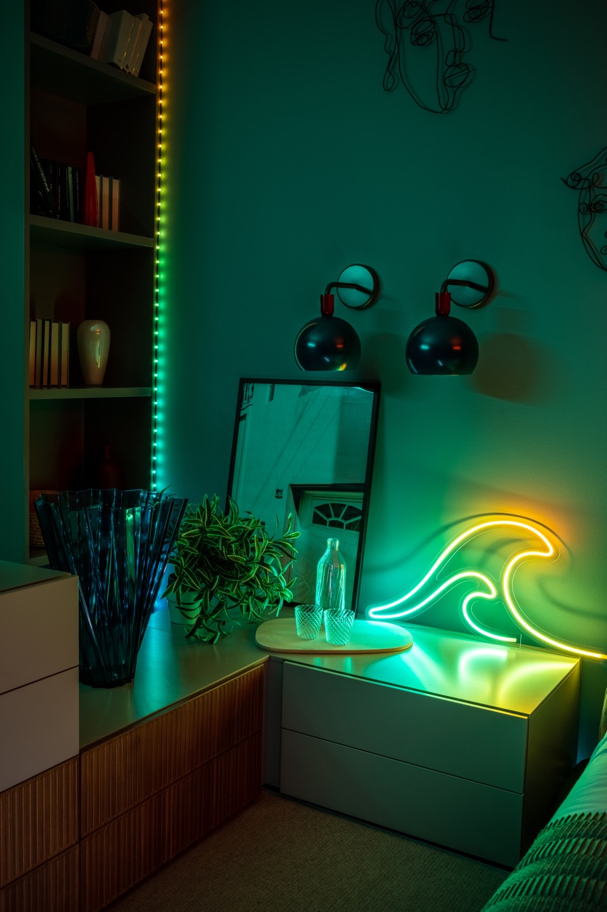 Una stanza con un'onda al neon, uno specchio e una libreria con luci colorate.