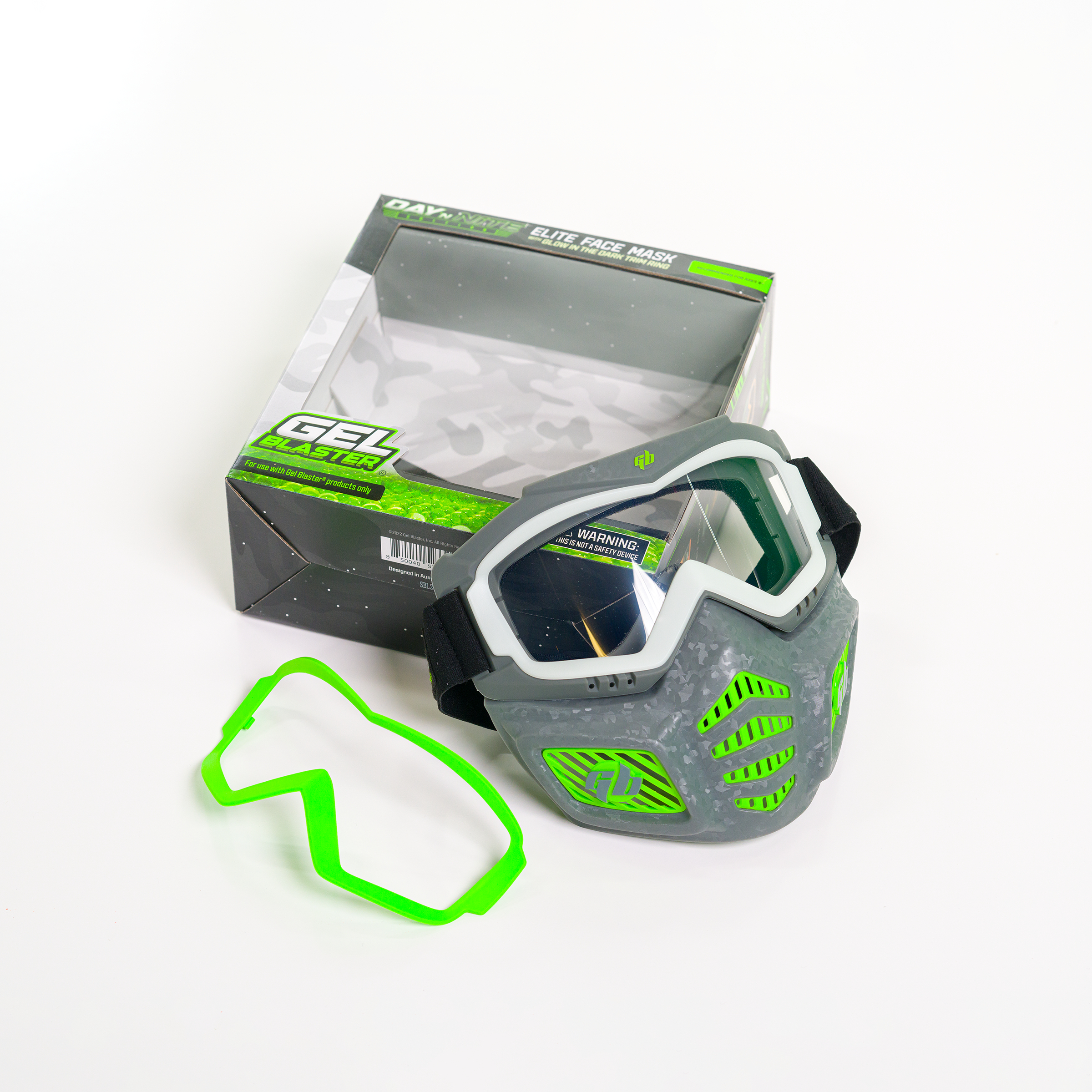 Graue und grüne Paintballmaske und ein grüner Schutzrahmen neben einer Produktbox.