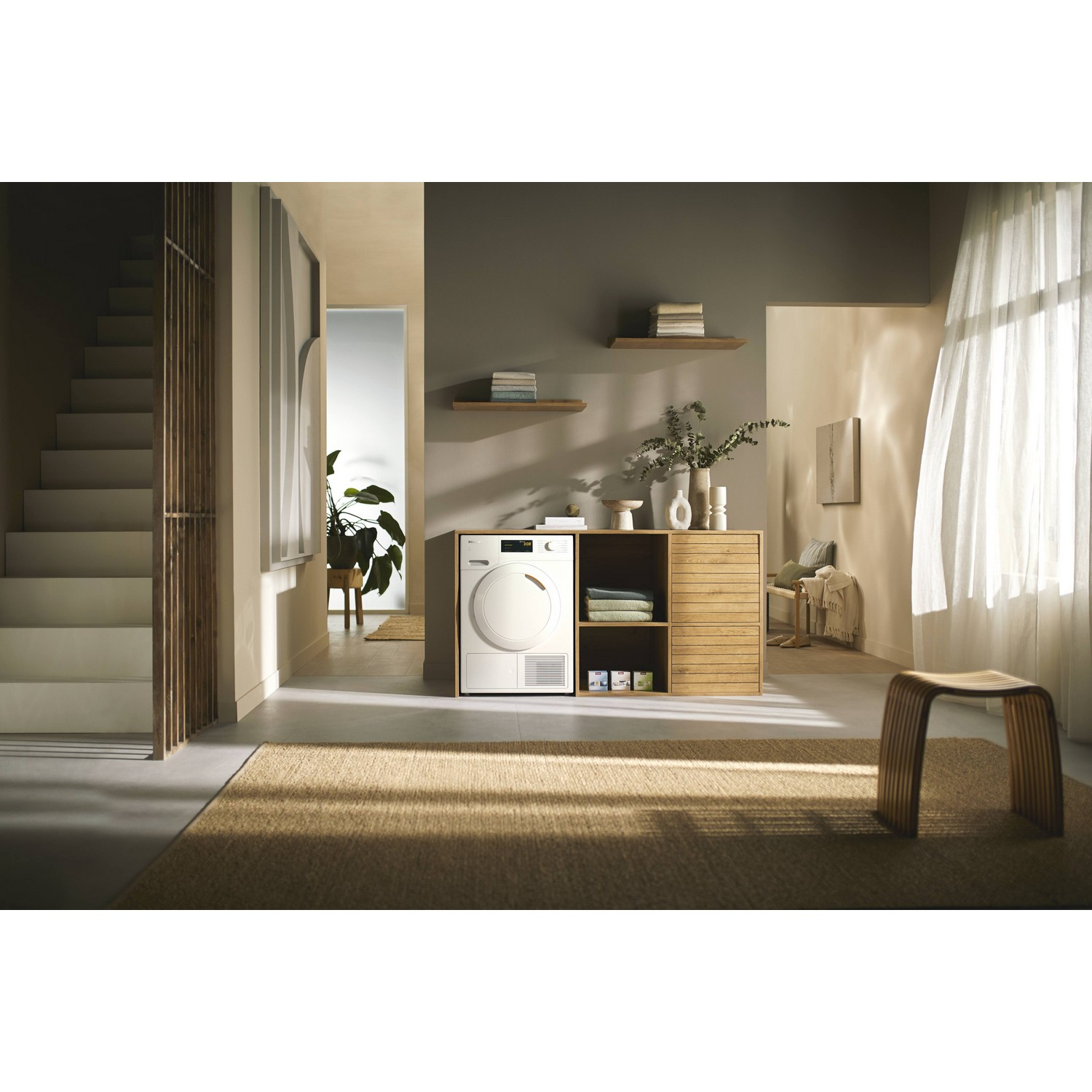 Moderne wasruimte met een wasmachine, houten kast en een vloerkleed. Neutraal kleurenschema.