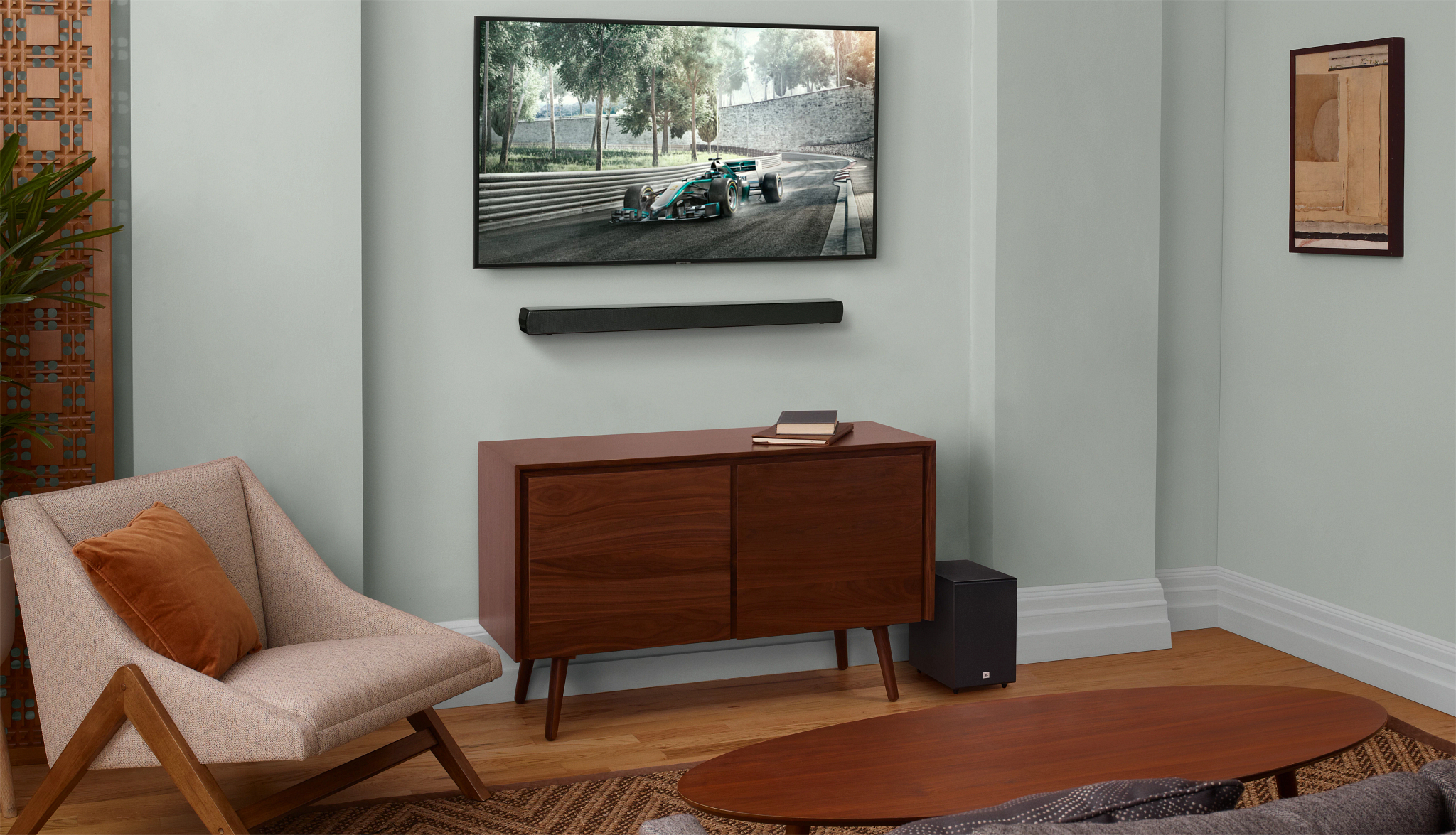 Wohnzimmer mit Fernseher, Soundbar und Subwoofer. Brauner Schrank, Stuhl und Kunstwerk vorhanden.