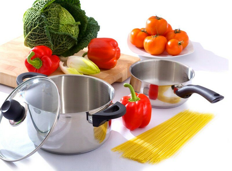 Warzywa i garnki na białej powierzchni. Zawiera czerwoną paprykę, spaghetti i kapustę.