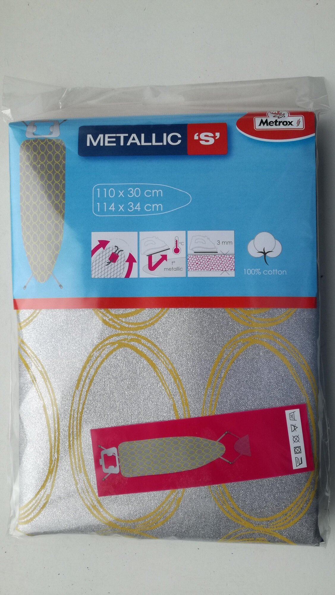 Pokrowiec na deskę do prasowania, srebrno-złoty wzór. Etykieta z napisem 'Metallic S' i 'Metrax'.