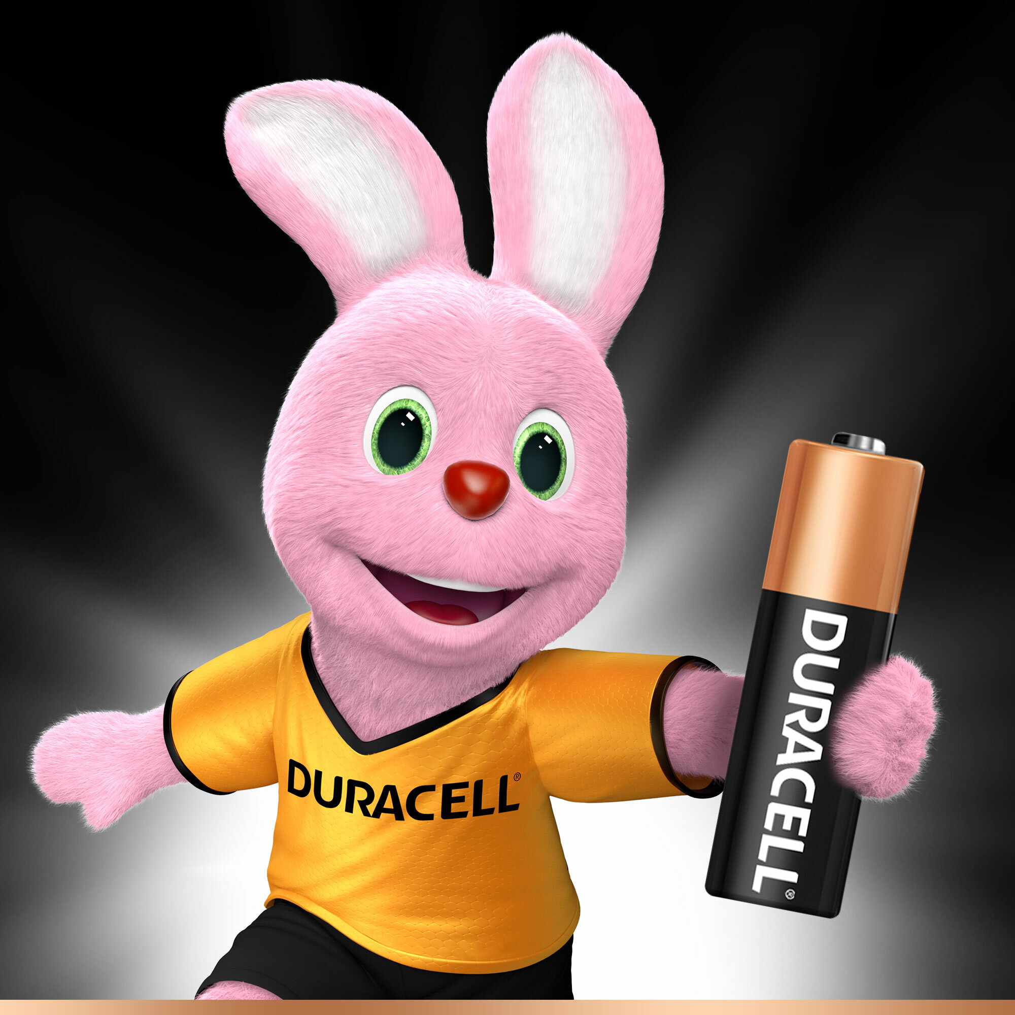 Różowy królik Duracell trzymający baterię Duracell, w żółtej koszulce.