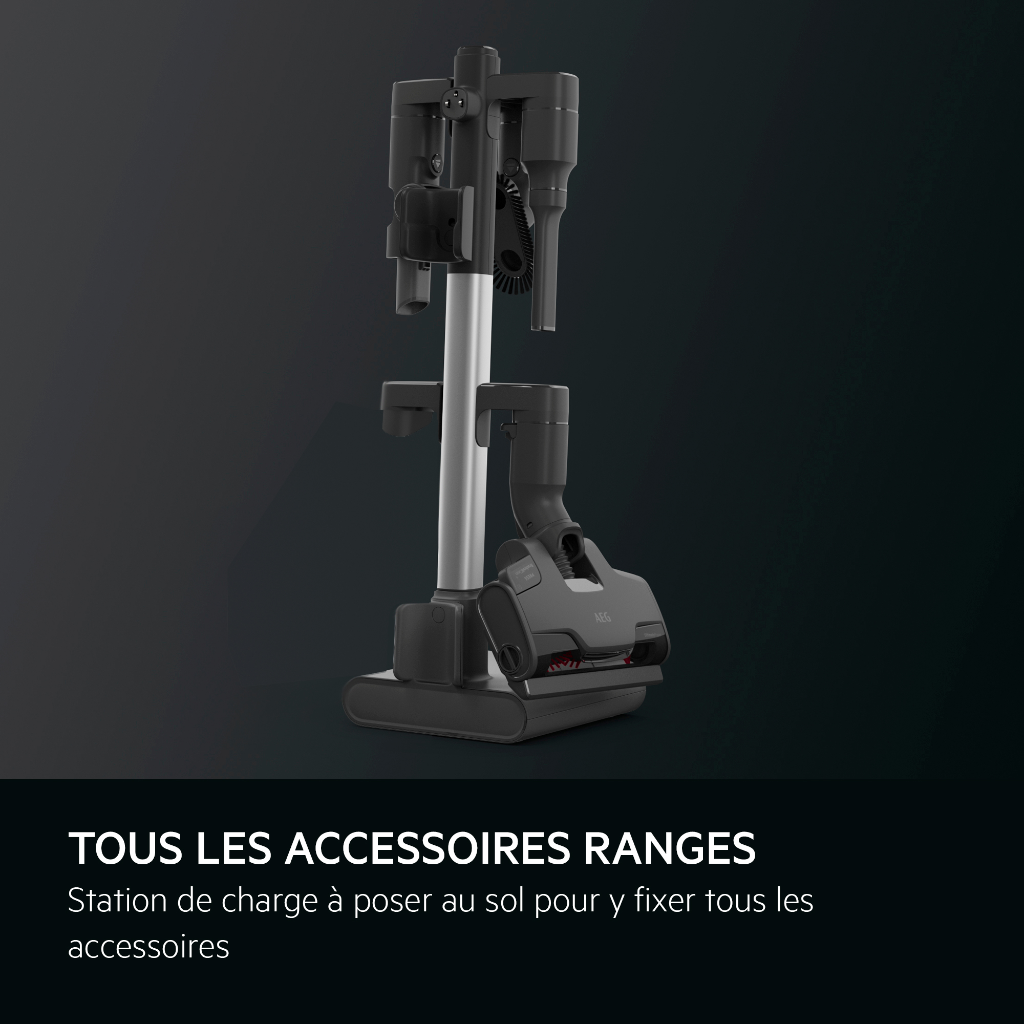 Un support d'aspirateur noir avec accessoires. Le texte indique : 'TOUS LES ACCESSOIRES RANGES'.