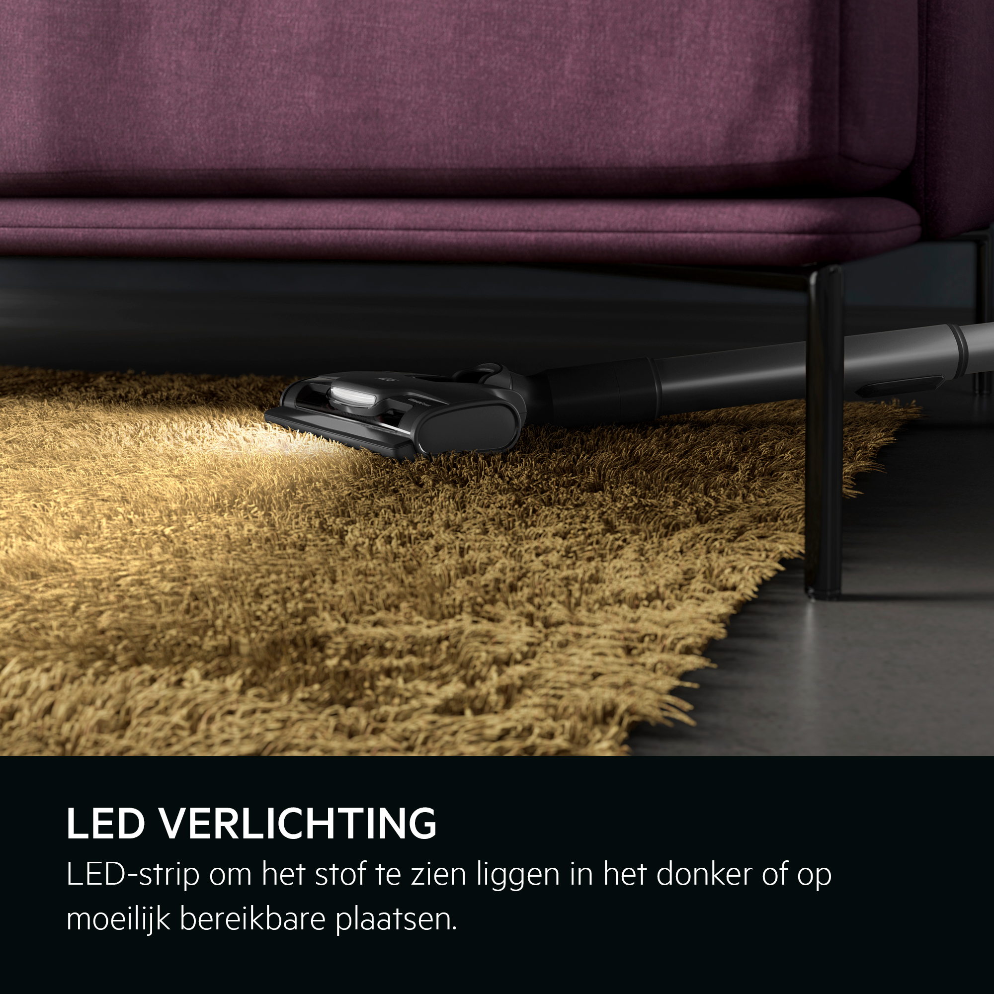 A vacuum cleaner head under a purple couch on a yellow rug. The light is on.