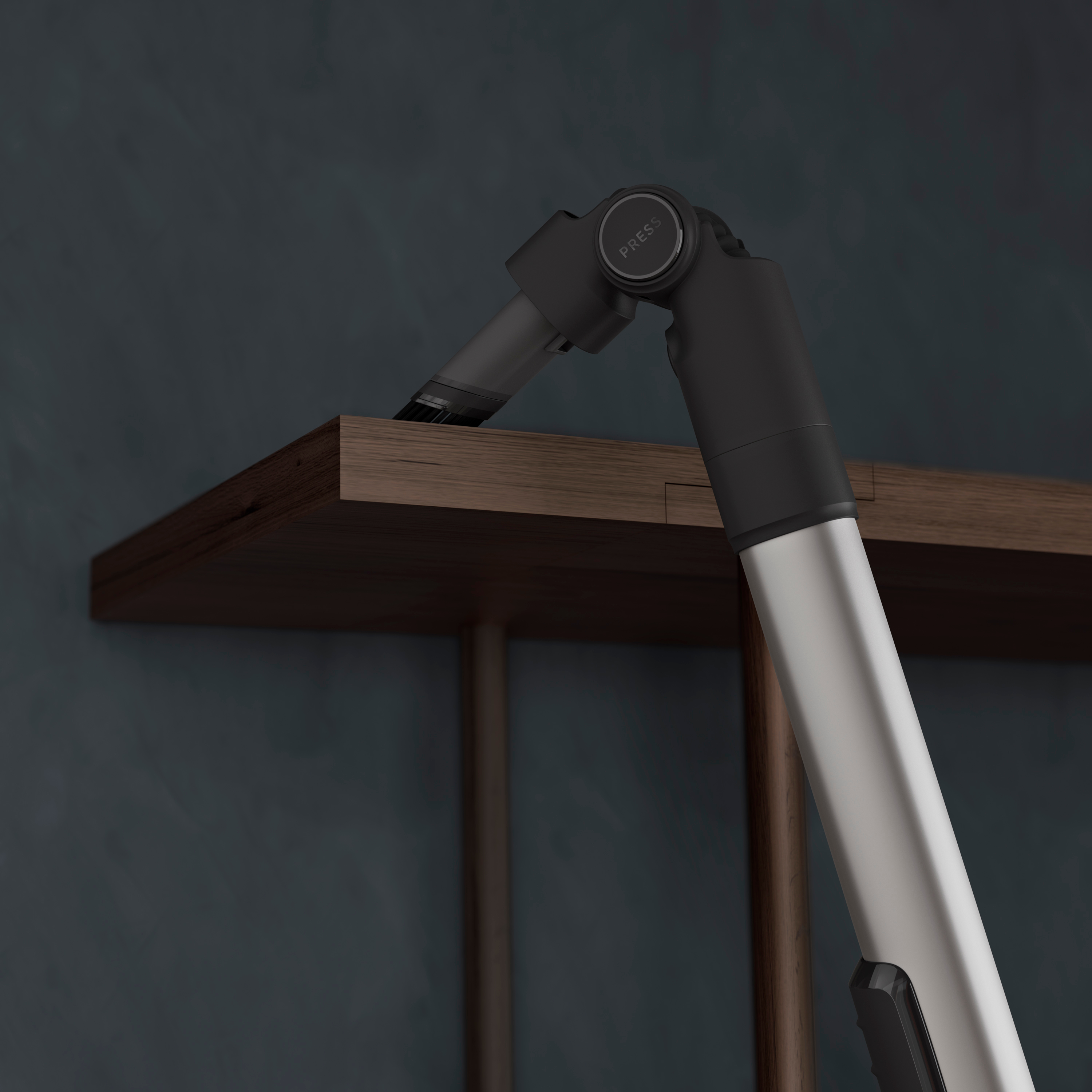 A detail of a vacuum cleaner, the head angled, cleaning the edge of a wooden shelf.