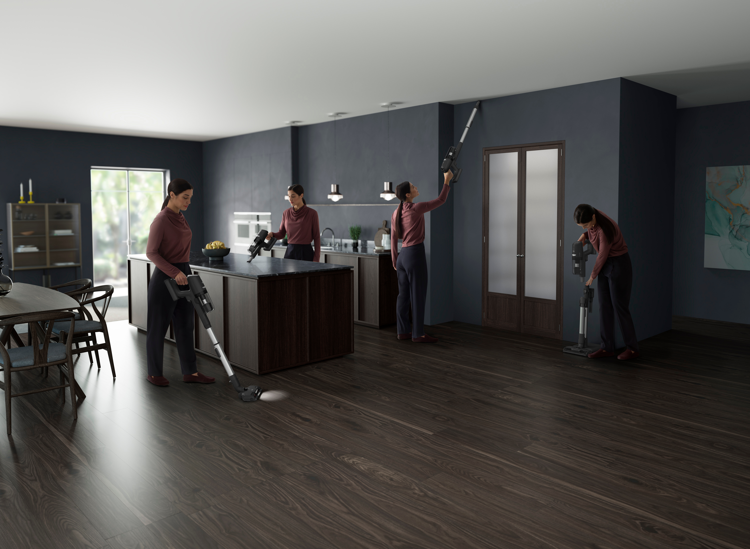 Four women vacuuming a kitchen. One vacuums the floor, three reach walls and ceiling. Dark wood floor and cabinets.