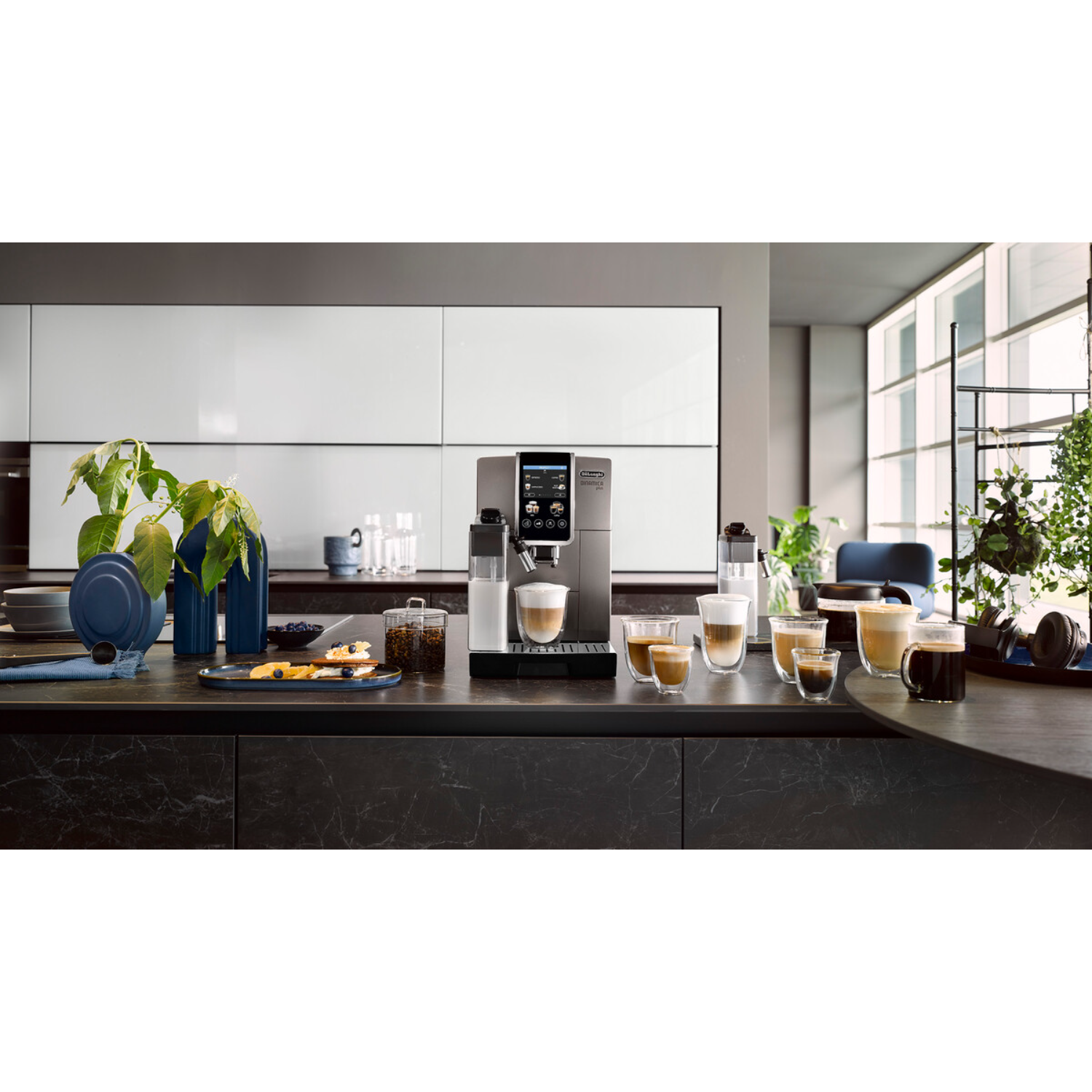 Coffee machine on a kitchen counter with coffee cups and pastries. White kitchen.