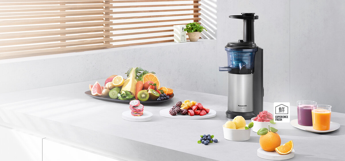 Wycinarka do soku na blacie z owocami i szklankami soku. Scena kuchenna z drewnianymi żaluzjami.