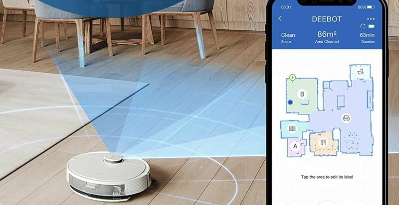 Biały robot sprzątający mapuje pokój niebieskimi liniami. Obok smartfon z aplikacją.