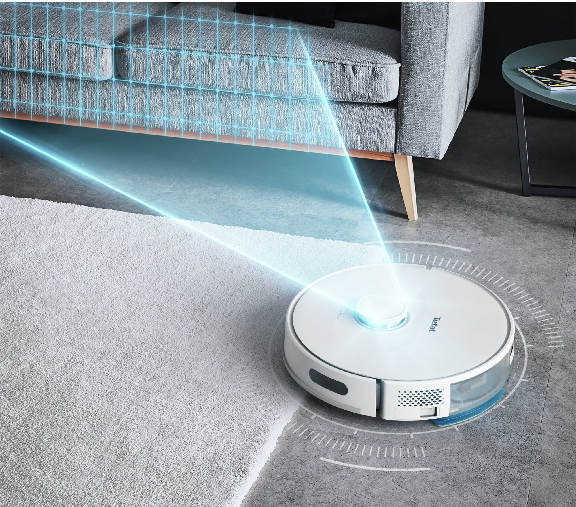 Biały odkurzacz robot sprząta jasnoszarą wykładzinę. Niebieskie linie pokazują ścieżkę czyszczenia.