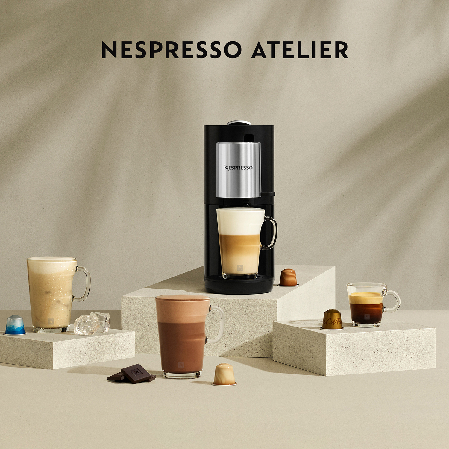 Macchina da caffè Nespresso Atelier con varie bevande al caffè e capsule in mostra.