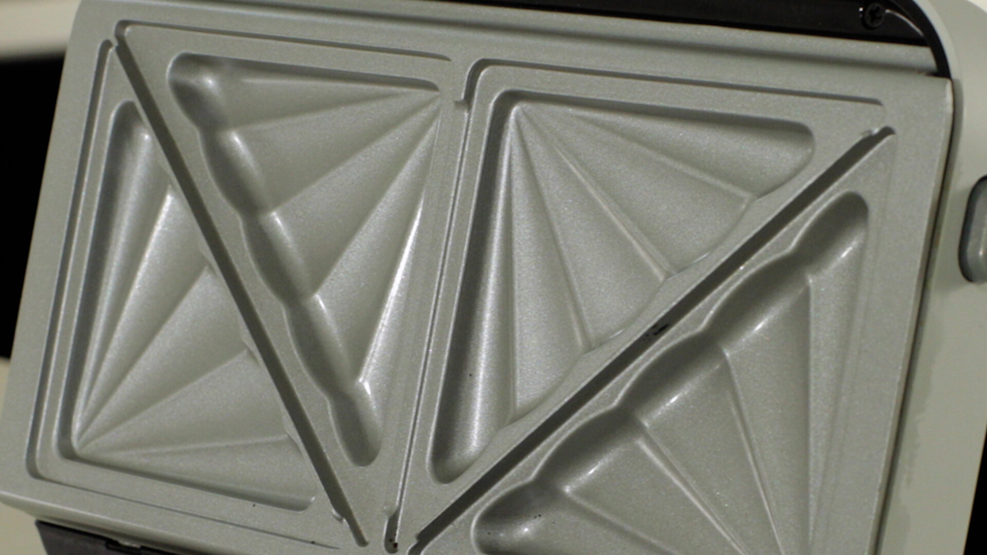 Zbliżenie wnętrza opiekacza do kanapek z dwiema trójkątnymi powierzchniami do gotowania.