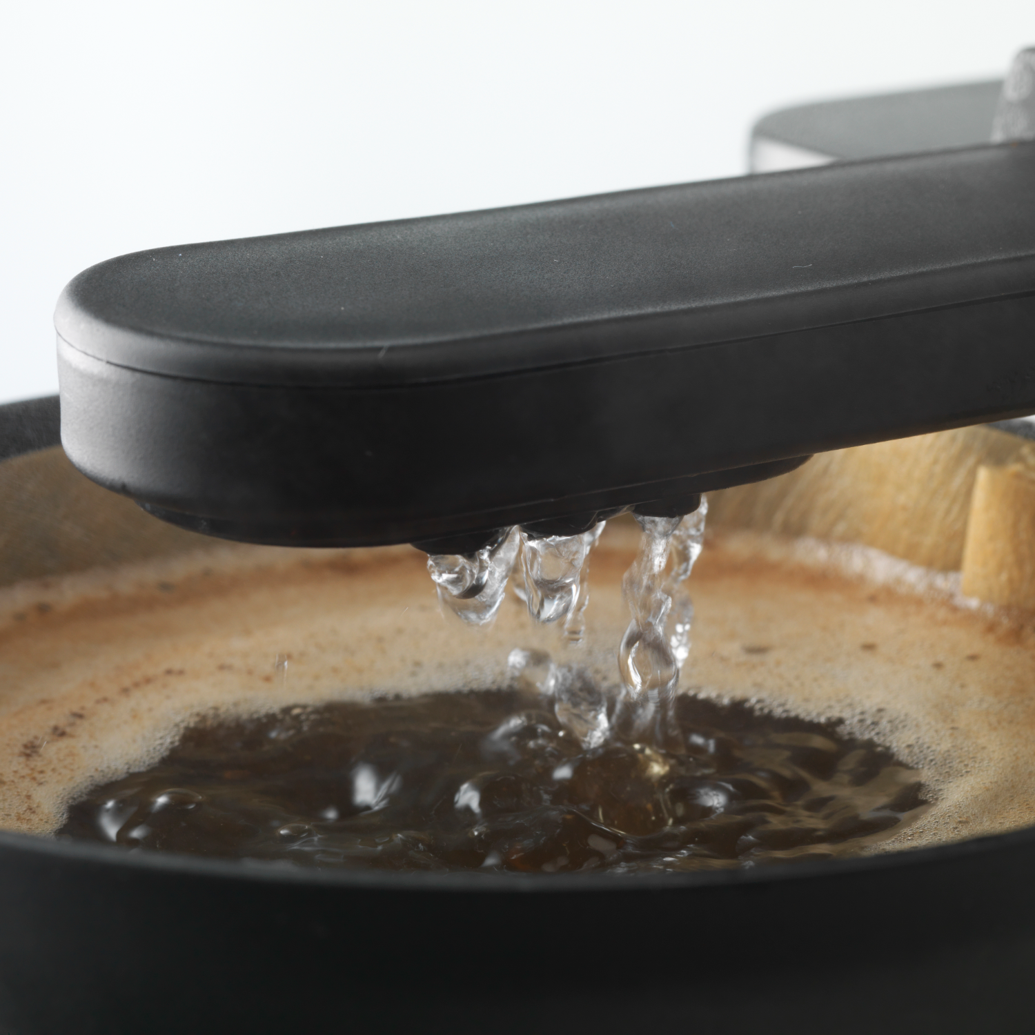 Water dat uit een zwart koffiezetapparaat in een filter giet.