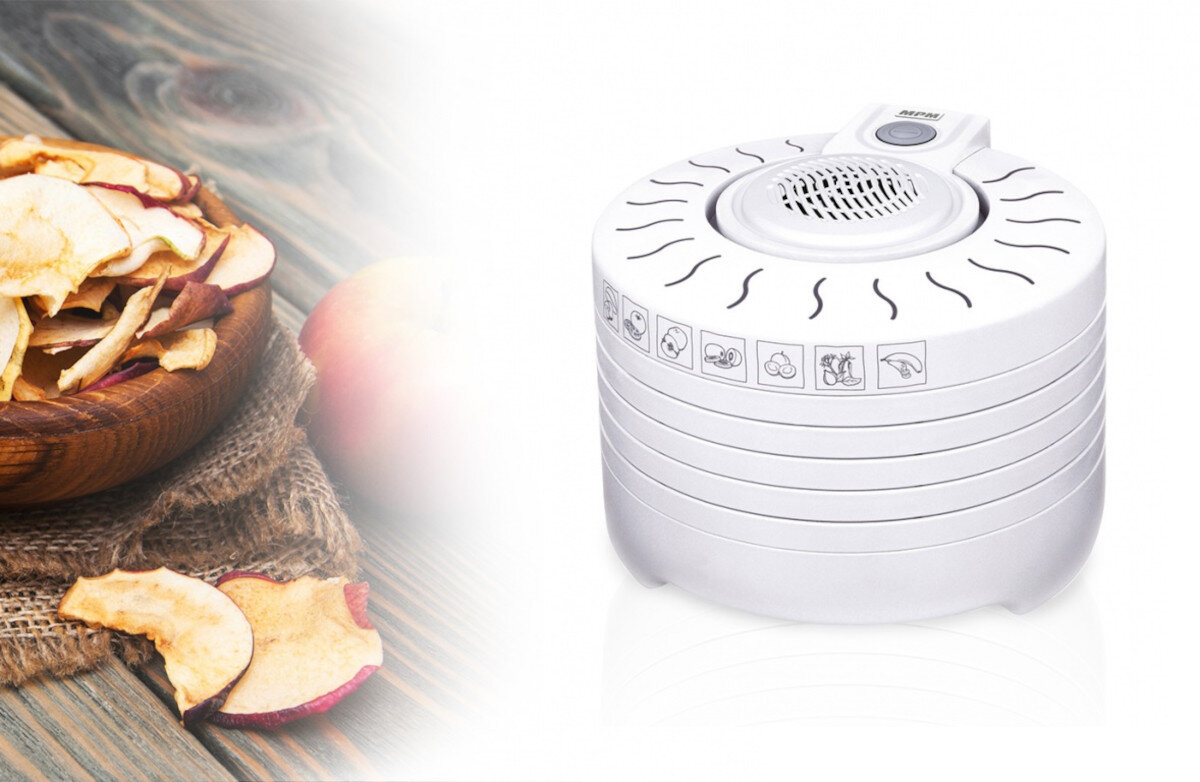 Suszarka do żywności z suszonymi plasterkami jabłka i jabłkiem w tle.