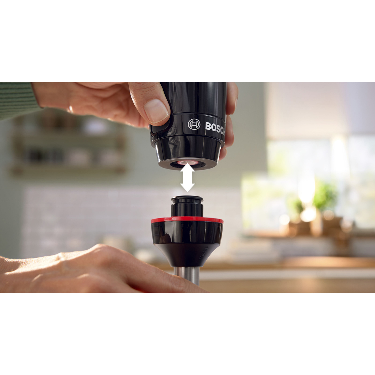 Primo piano di mani che assemblano un componente di un elettrodomestico da cucina nero e rosso.
